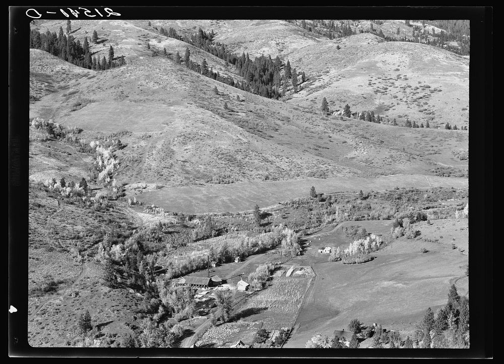 Looking down on Ola self-help co-op mill showing the upper end of Squaw Creek Valley, the creek lined with trees, the new…