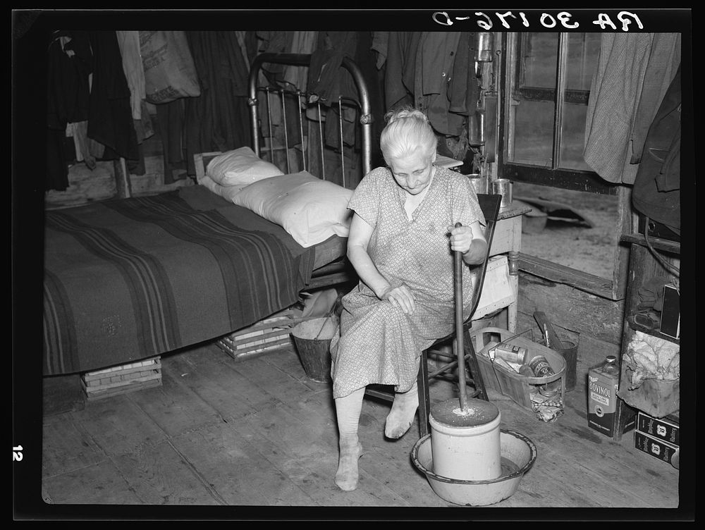 Member of Johnson family churning butter in her home near Black River Falls, Wisconsin by Russell Lee