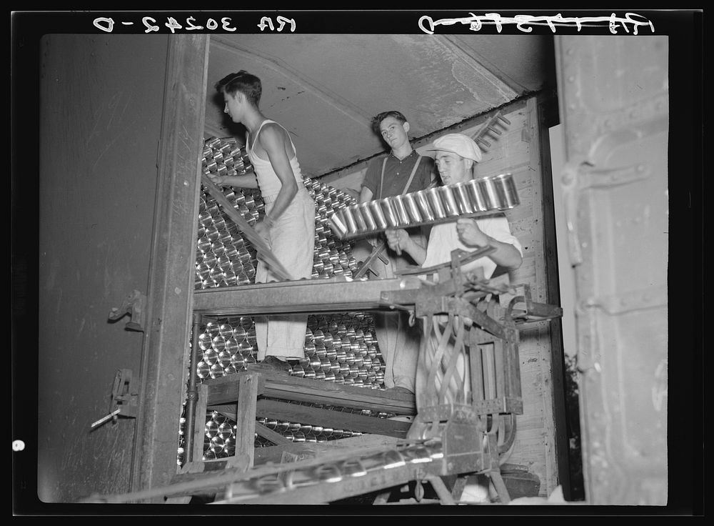 Unloading cans from boxcar. Canning factory, Sun Prairie, Wisconsin by Russell Lee