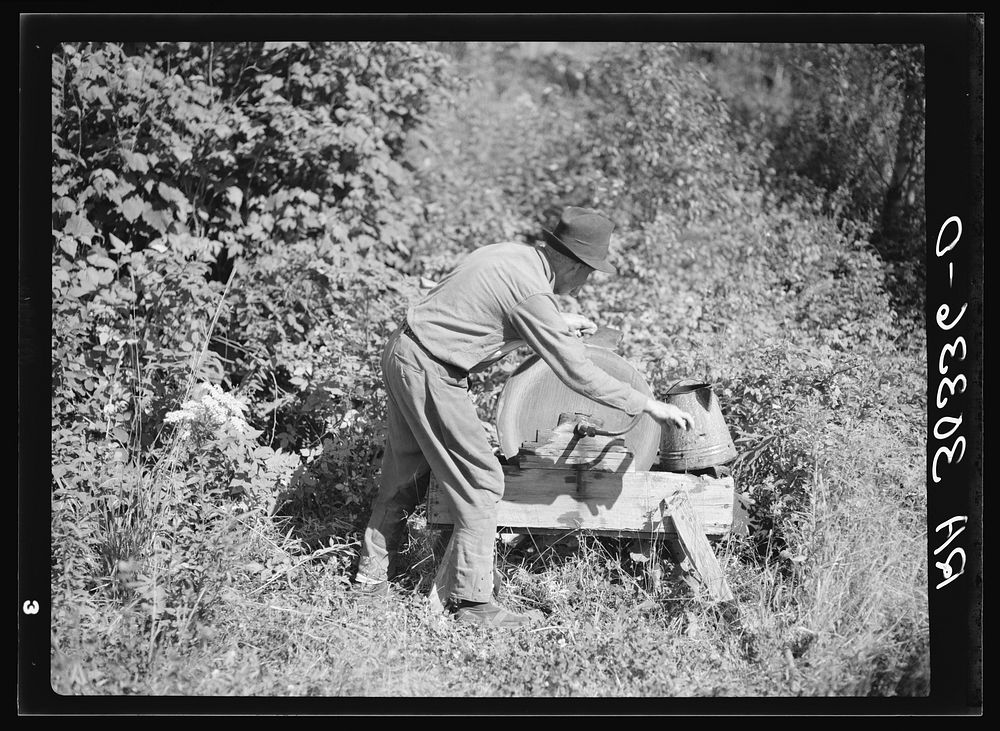 William Besson, old iron ore prospector, grinding an axe near Winton, Minnesota by Russell Lee