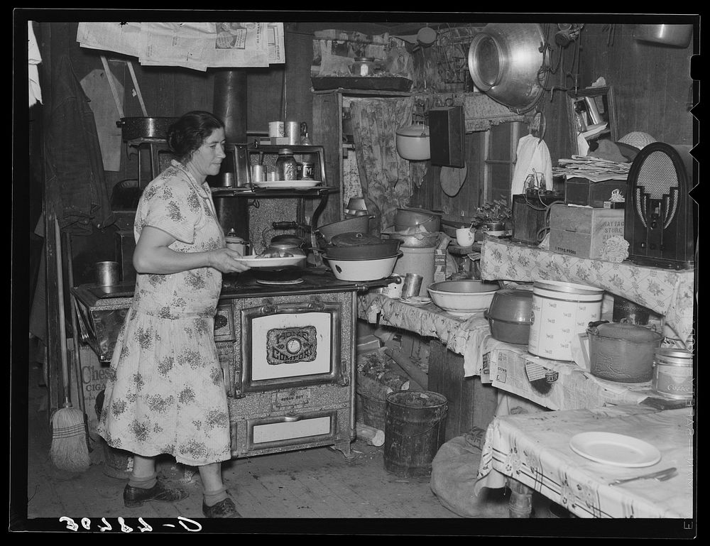 Mrs. Ole Thompson, wife of farmer, carrying food to the table. Williams County, North Dakota by Russell Lee