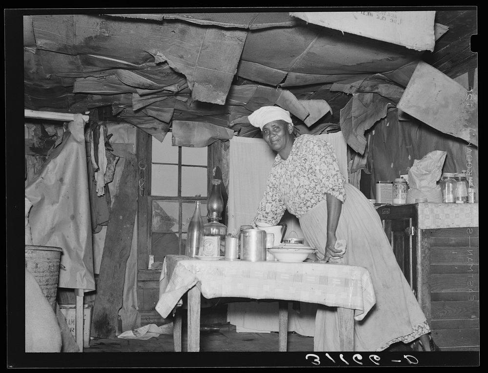 Southeast Missouri Farms. Wife of sharecropper working at table in kitchen of home. Note condition of ceiling by Russell Lee