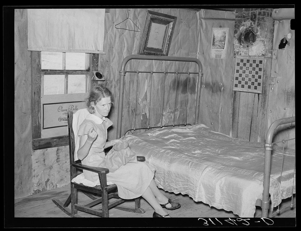 Southeast Missouri Farms. Sharecropper's daughter sewing in combination living room/bedroom of shack home. La Forge project…