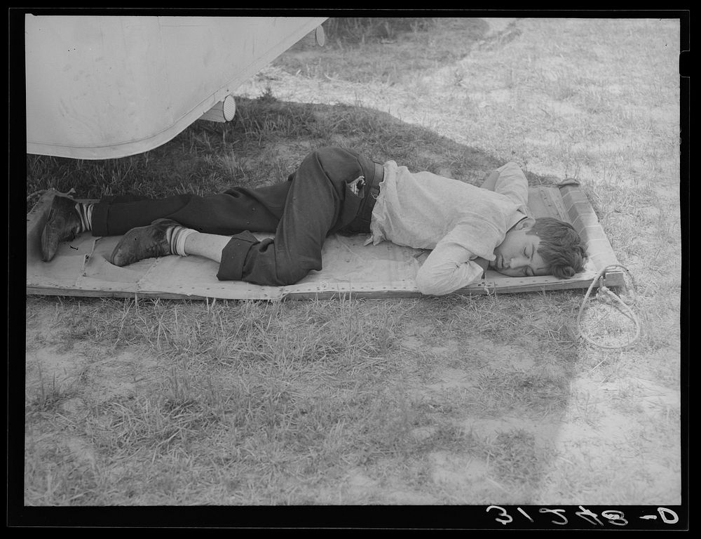 Member of carnival crew resting on hammock. Lasses-White traveling show.  Sikeston, Missouri by Russell Lee