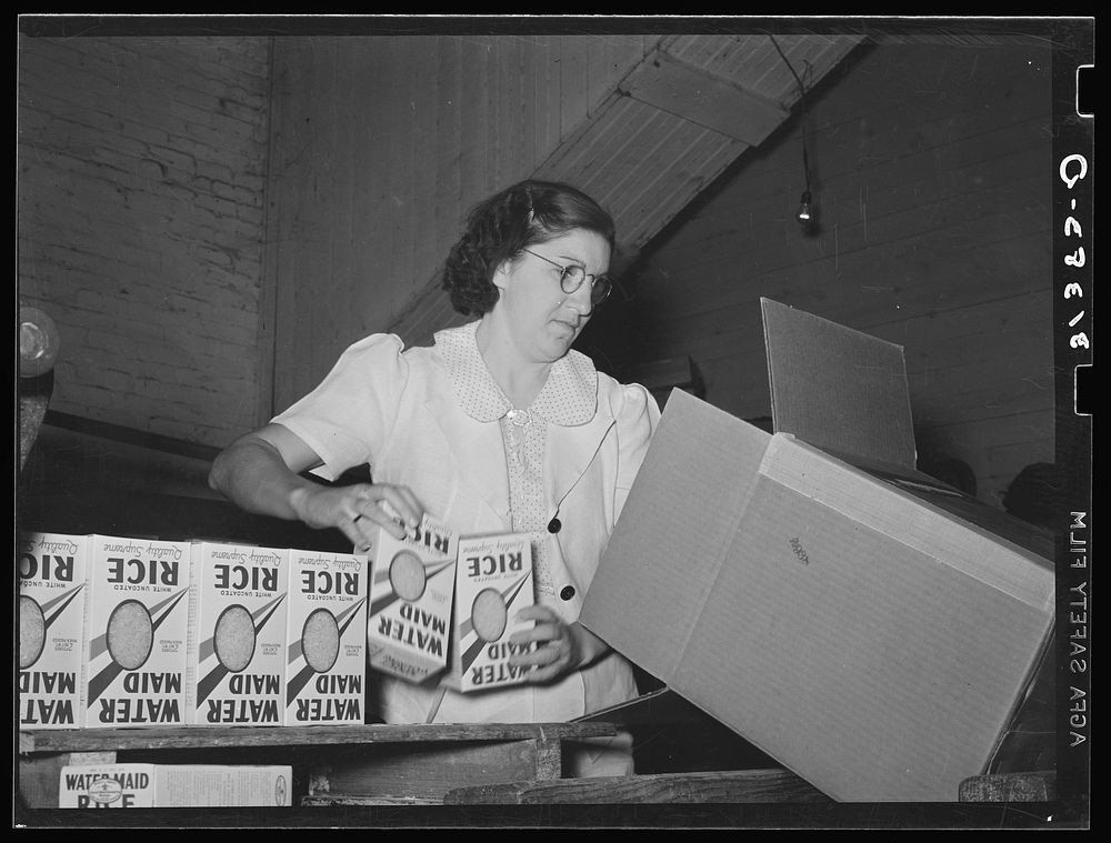 Removing packages of rice from conveyer to place them in fiber cartons.  State rice mill, Abbeville, Louisiana by Russell Lee