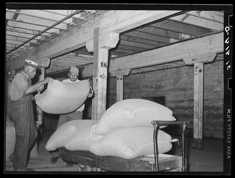 Loading sacks of rice onto trucks in warehouse. State rice mill, Crowley, Louisiana by Russell Lee