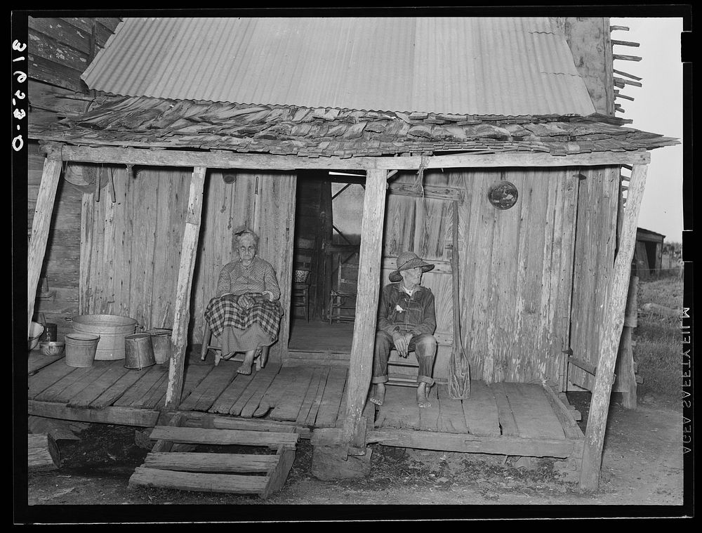 Aged couple sitting on front porch of farm home near Crowley, Louisiana by Russell Lee