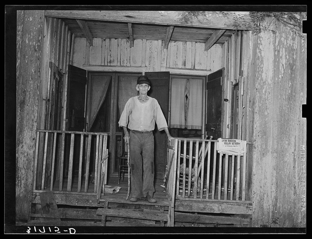 Old man standing on front of recessed porch in house near Lutcher, Louisiana by Russell Lee