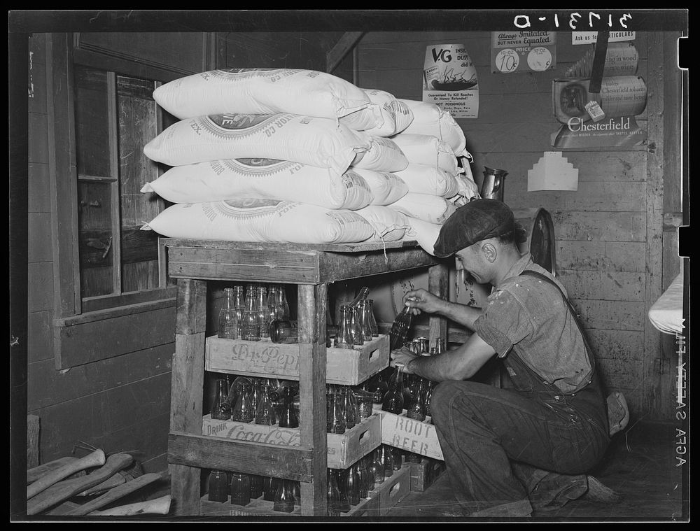 Corner of grocery store with man taking bottled drinks from supplies to fill ice box. Near New Iberia, Louisiana by Russell…