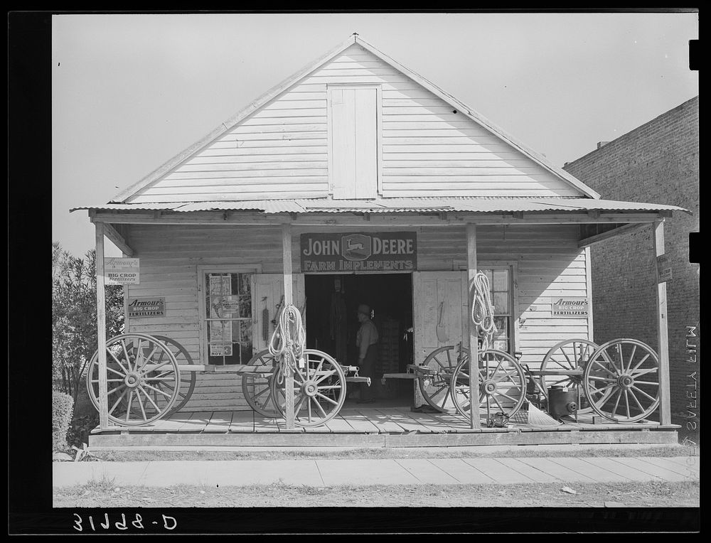 Wagons on porch of farm implements dealer. Erath, Louisiana by Russell Lee