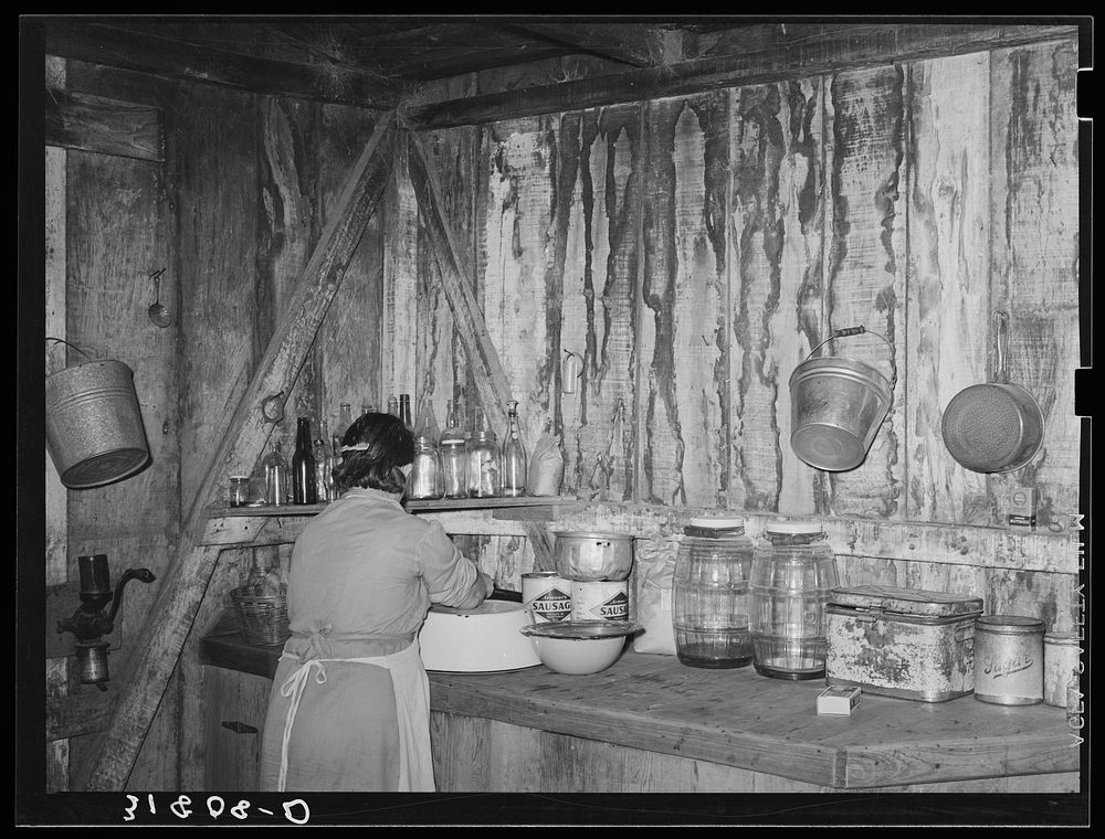 Mrs. M. LaBlanc straightening articles in corner of kitchen in present home. Note the waterstained walls caused by leaking…