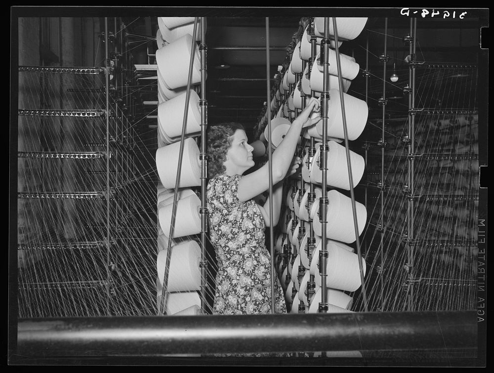 Girl tending spools of cotton in winding process. Laurel mills, Laurel, Mississippi by Russell Lee
