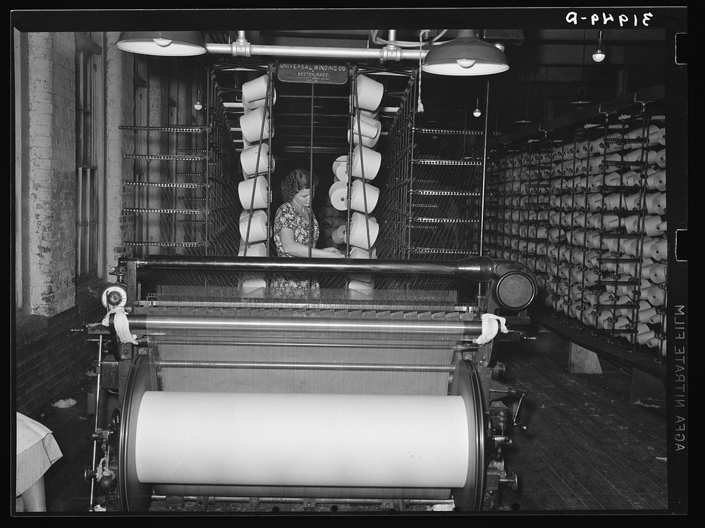 Girl tending spools of cotton in winding process. Laurel, Mississippi by Russell Lee