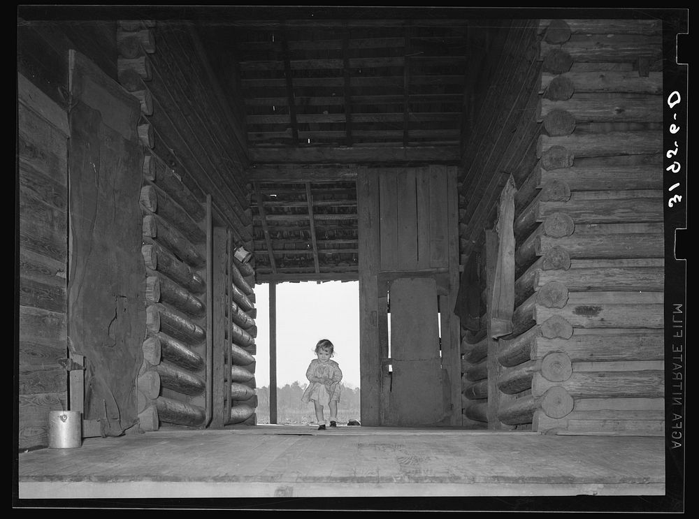 [Untitled photo, possibly related to: Child of Ed Baggett, sharecropper, walking through open space in dog trot cabin near…