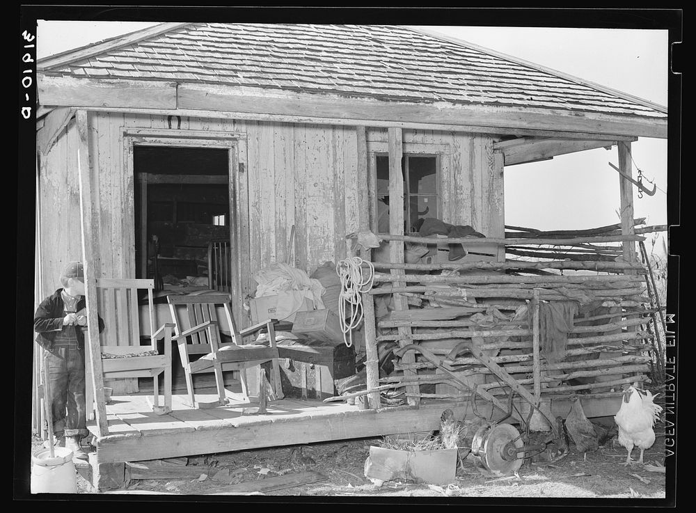 Goods stored on front porch of former sharecropper's cabin, now temporary home of FSA (Farm Security Administration) client.…