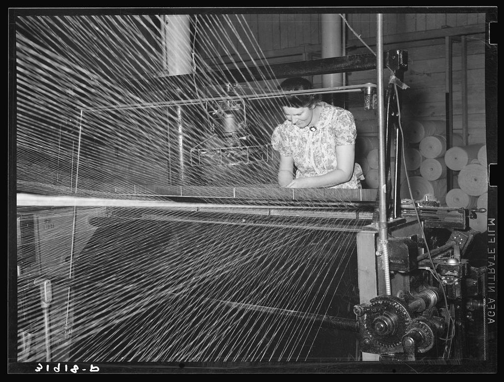 Operator of winding machine in Laurel Cotton Mill repairing break in thread. Laurel, Mississippi by Russell Lee