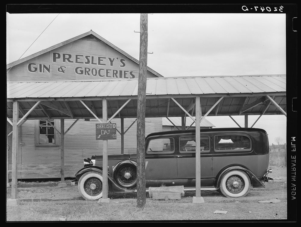 Funeral ambulance parked under gin shed. Mound Bayou, Mississippi by Russell Lee