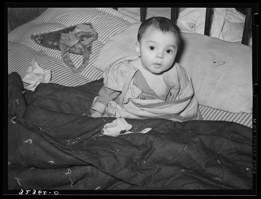 Mexican child in bed. The baby has impetigo. Crystal City, Texas by Russell Lee