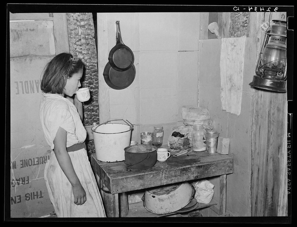 Mexican girl drinking a cup of water in the kitchen of her home in San Antonio, Texas by Russell Lee
