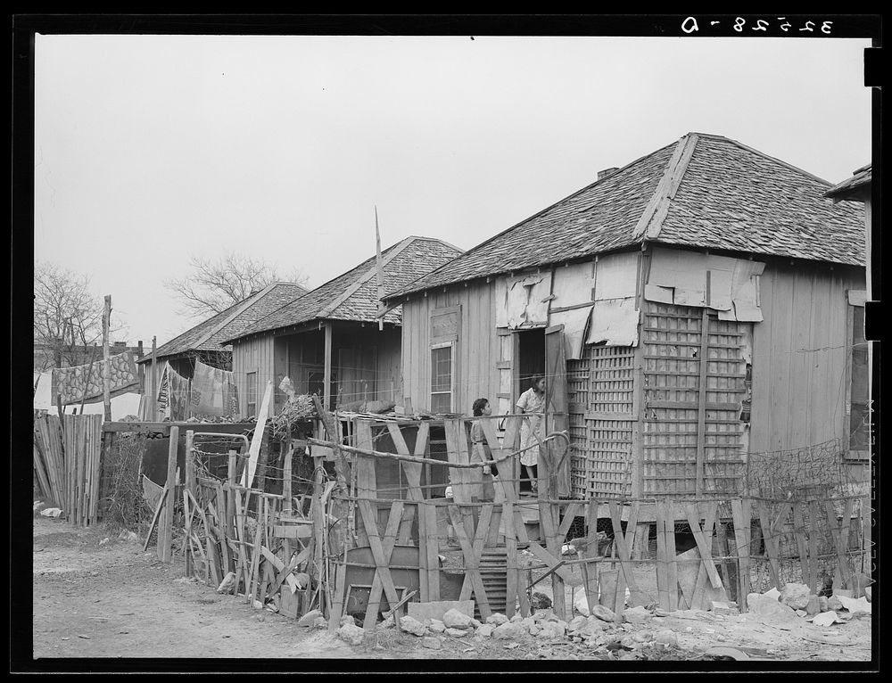 Row of Mexican houses. San Antonio, Texas. Notice crude fences and state of disrepair of houses by Russell Lee
