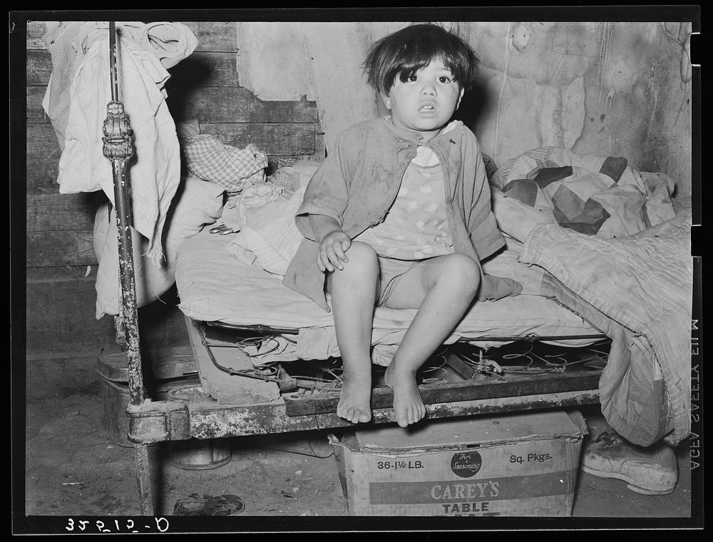 Mexican child sitting on bed. San Antonio, Texas by Russell Lee