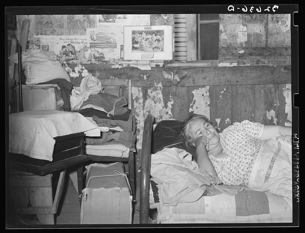 Mexican woman resting on bed in her home. San Antonio, Texas by Russell Lee