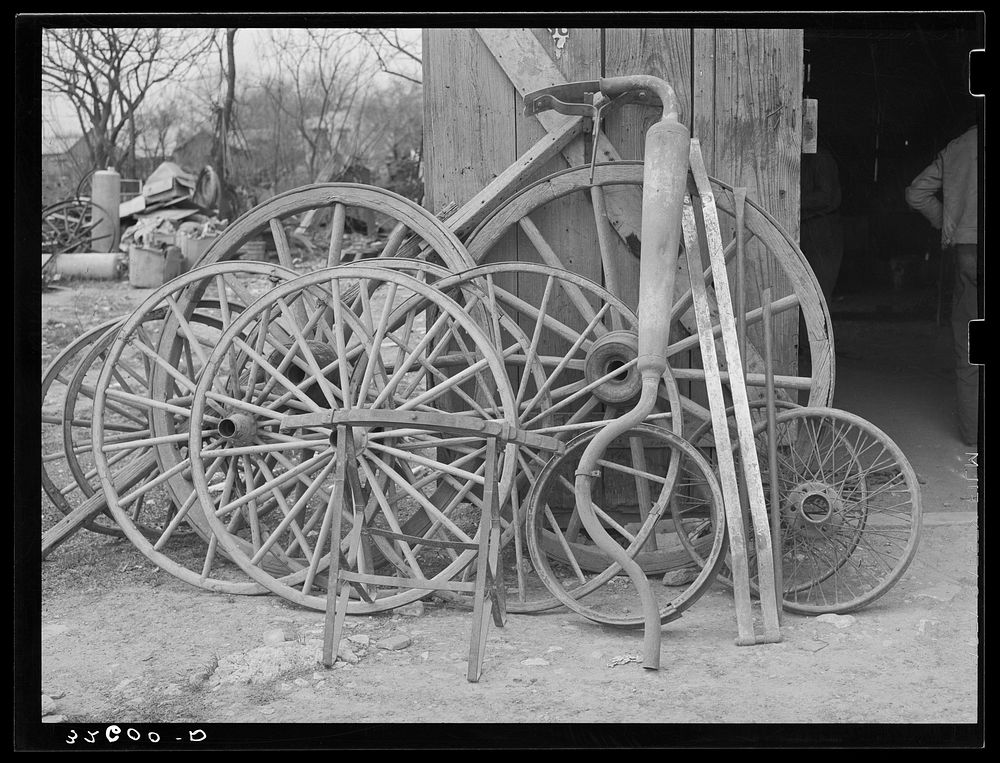 Wagon wheels and automobile exhaust pipes in front of smith shop. San Antonio, Texas by Russell Lee