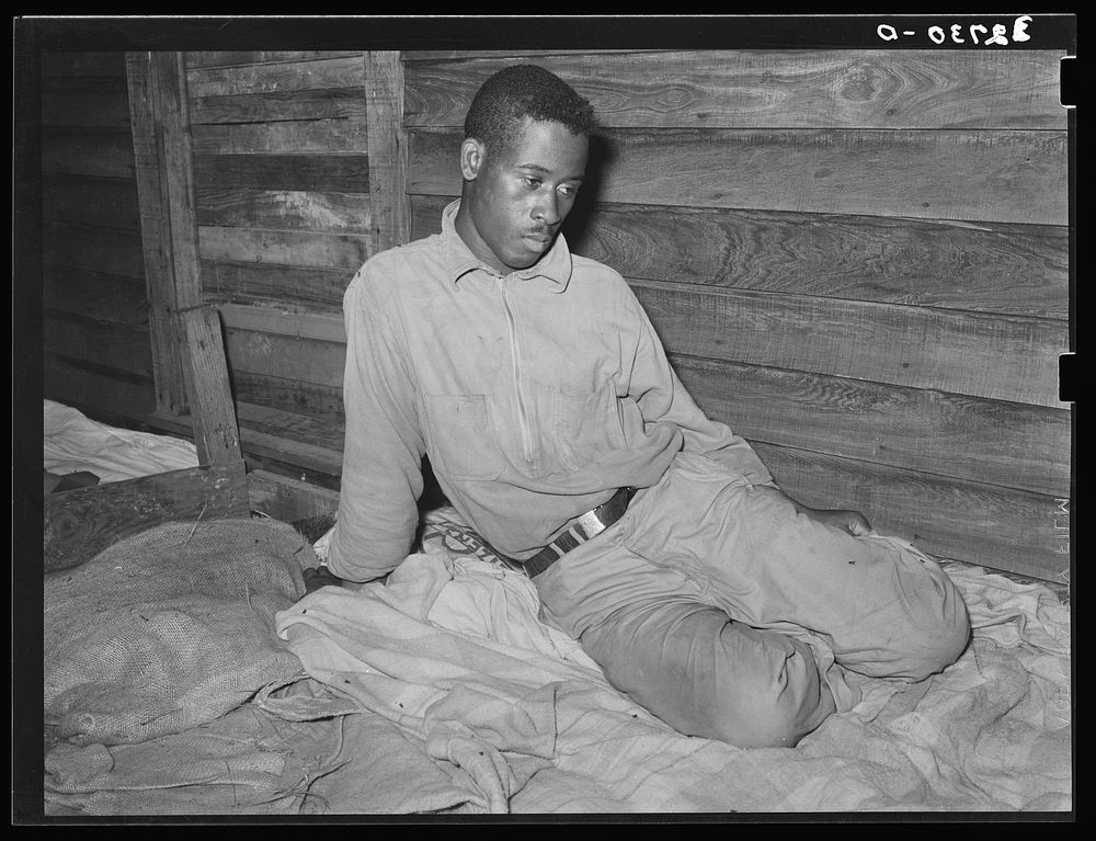  strawberry worker sitting on his bunk in bunkhouse. Hammond, Louisiana by Russell Lee