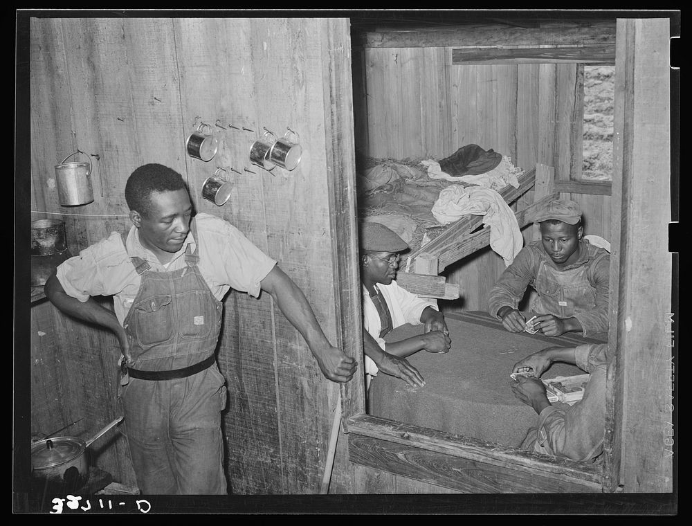 Poker game in  strawberry workers' bunkhouse. Note the crude bunk. Near Hammond, Louisiana by Russell Lee
