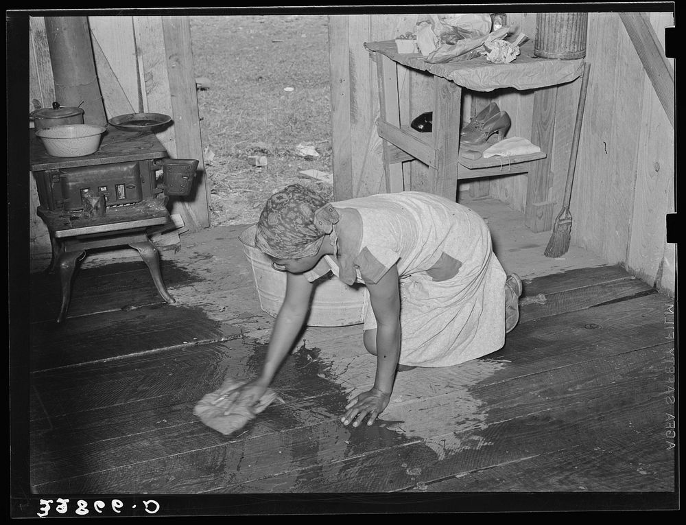  woman, strawberry picker, scrubbing the floor of her living quarters near Hammond, Louisiana by Russell Lee