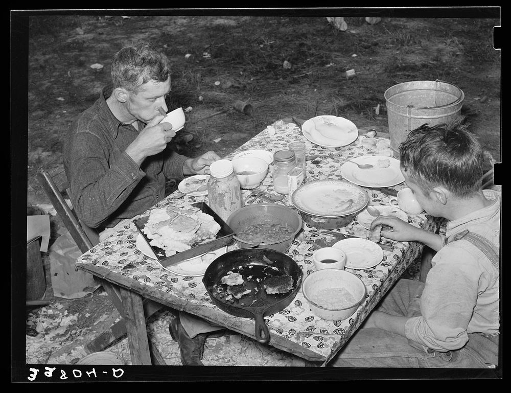 White migrant berry picker and son eating dinner near Hammond, Louisiana by Russell Lee