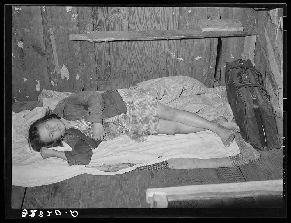 Daughter of migratory berry picker taking a nap on her bed on the floor.  Near Ponchatoula, Louisiana by Russell Lee