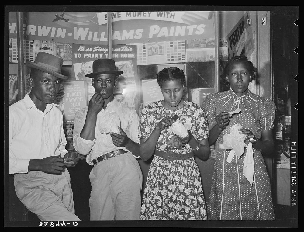 People eating ice cream in front of hardware store. San Augustine, Texas by Russell Lee
