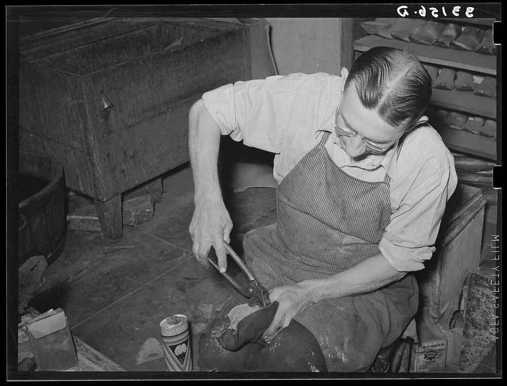 [Untitled photo, possibly related to: Bootmaker putting last and sole into upper part of boot. Boot shop, Alpine, Texas] by…