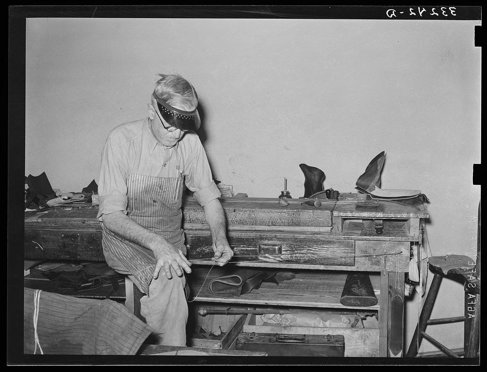 Preparing waxed thread by rolling thread between hand and knee. Boot shop, Alpine, Texas by Russell Lee