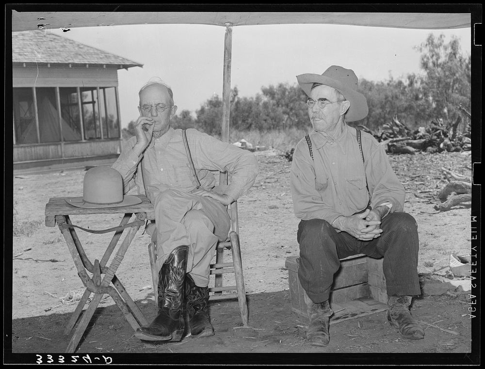 Foreman of the SMS Ranch on left and old cowboy on the right waiting for dinner at the chuck ragon. Ranch near Spur, Texas…