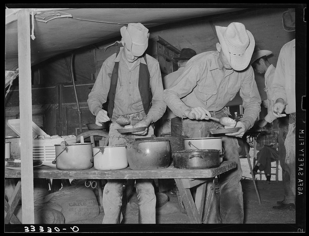 Cowboys of the SMS Ranch serving themselves at dinner at chuck wagon. Ranch near Spur, Texas by Russell Lee