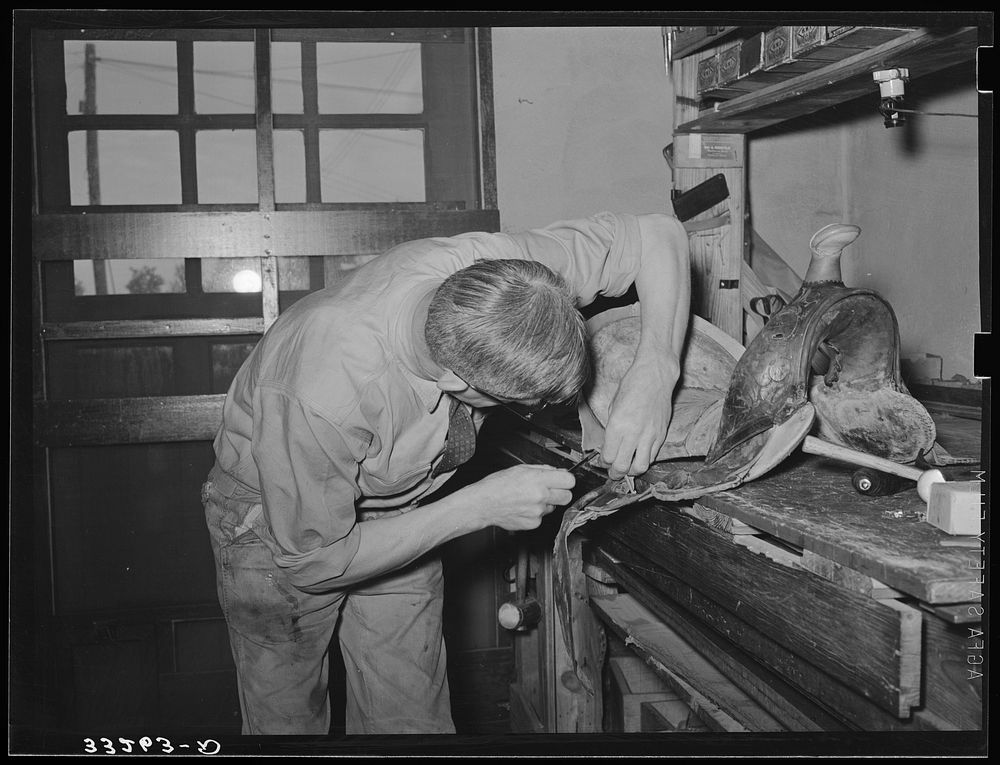 Saddle maker sewing saddle while repairing it. Saddle shop, Alpine, Texas by Russell Lee