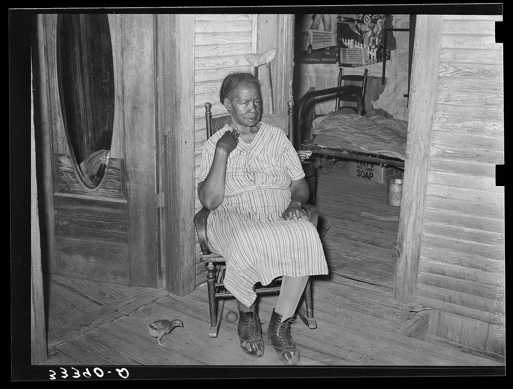 Mother of  agricultural day laborer on porch of her home. She was crippled with rheumatism. Muskogee County, Oklahoma by…