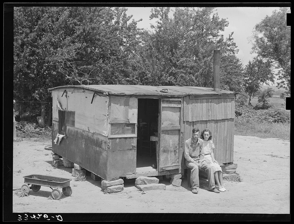 WPA (Works Progress/Work Projects Administration) worker and his wife sitting in front of their shack home on the Arkansas…