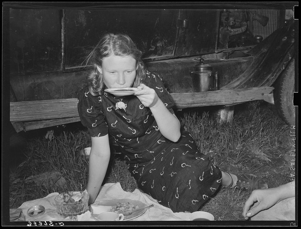 Migrant woman drinking coffee from saucer while camped near Prague, Oklahoma by Russell Lee