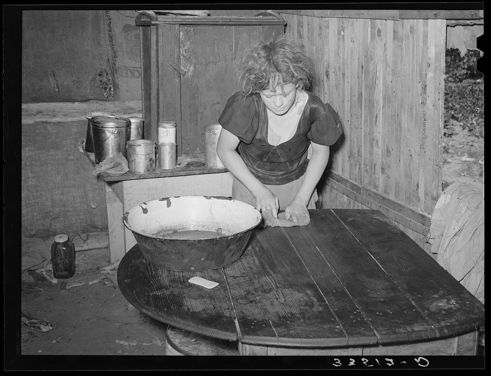 Daughter of agricultural day laborer doing work in the kitchen lean-to of their home. McIntosh County, Oklahoma by Russell…