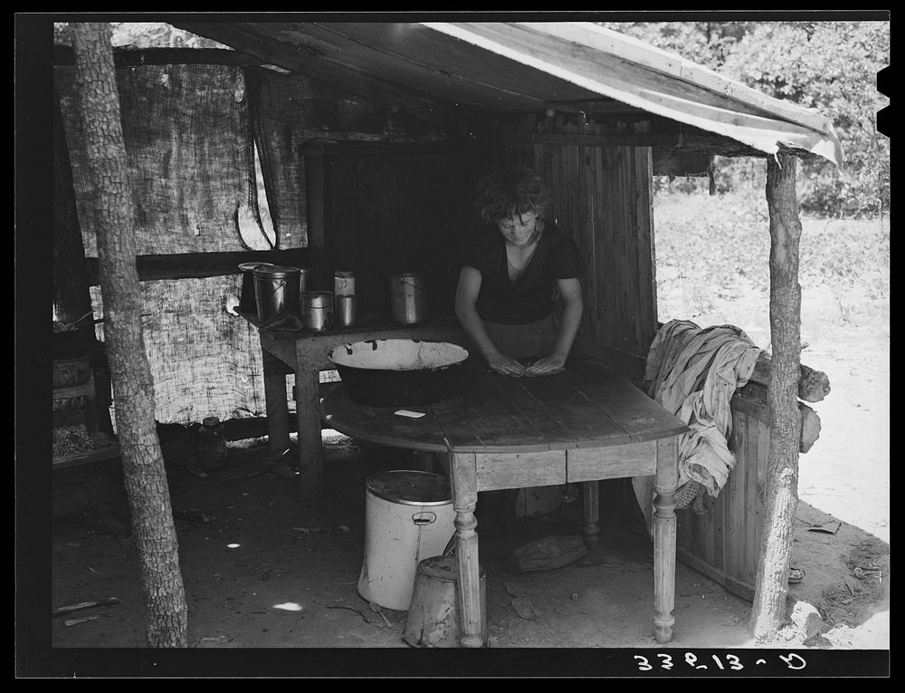 [Untitled photo, possibly related to: Daughter of agricultural day laborer doing work in the kitchen lean-to of their home.…