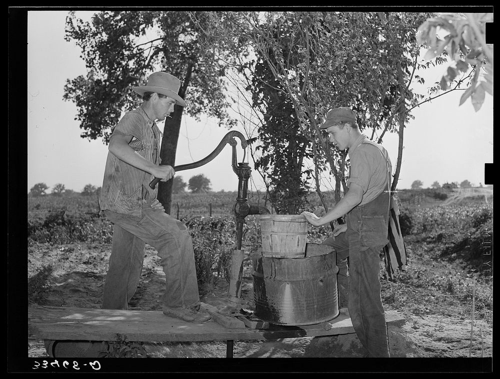 Migrant boys pumping water at their shack home near Muskogee. Muskogee County, Oklahoma by Russell Lee