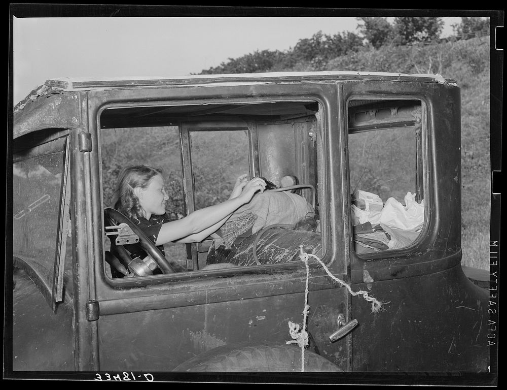 Migrant woman reaching in automobile for supplies while camped near Prague, Oklahoma. Lincoln County, Oklahoma by Russell Lee