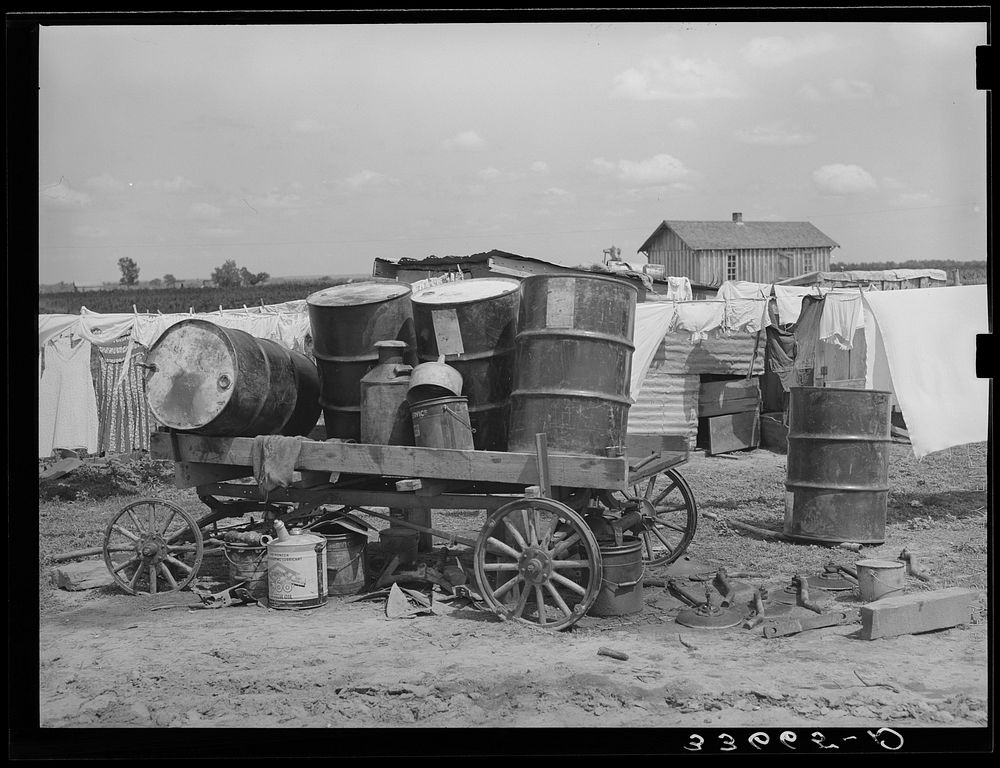 Scene on a tractor farm. Trailer loaded with oil drums. In Arkansas River bottoms near Vian, Oklahoma. Former tenant farmer…