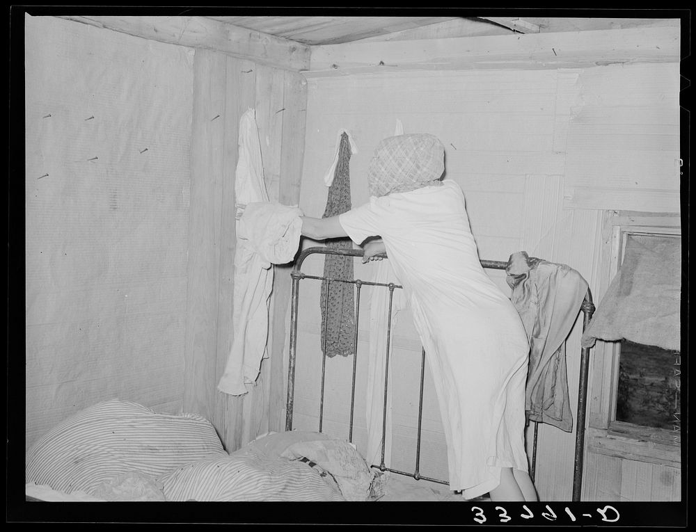 Interior of migrant's home near Muskogee, with mother removing articles of clothing preparatory for departure to California.…