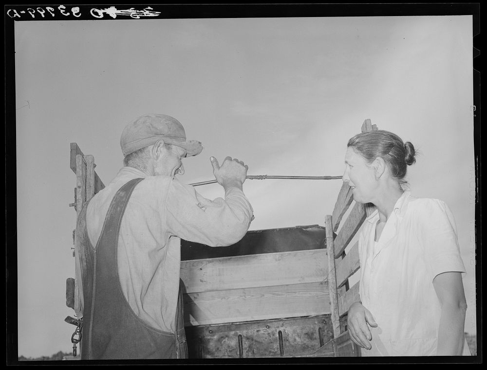 Migrant man and woman at rear of their truck before departure for California from Muskogee, Oklahoma by Russell Lee