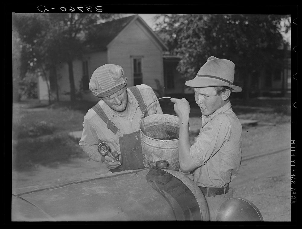 [Untitled photo, possibly related to: Pouring water into radiator of migrant's car in the streets of Muskogee, where family…