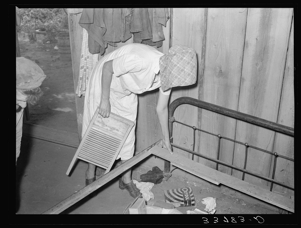 Removing wooden slats from bed. This bed will be taken by migrant family to California from Muskogee, Oklahoma by Russell Lee